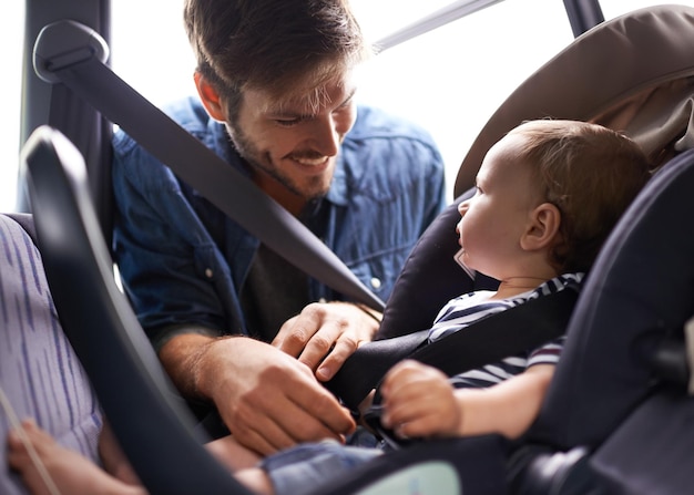 La sicurezza prima di tutto Un giovane padre che lega il suo bambino a un seggiolino per auto