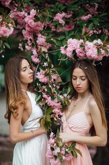 La signora alla moda sta posando vicino a un albero in fiore. Twin Girls Bellezza e moda femminile.