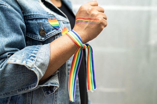 La signora asiatica che indossa i braccialetti della bandiera arcobaleno simbolo del mese dell'orgoglio LGBT celebra l'annuale a giugno sociale dei diritti umani transgender bisessuali gay lesbiche