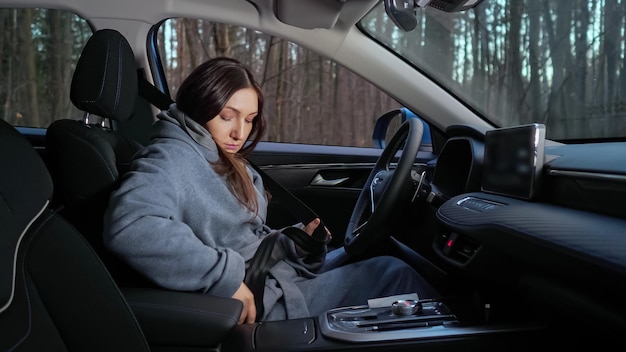 La signora conducente allaccia la cintura di sicurezza seduta al volante dell'auto