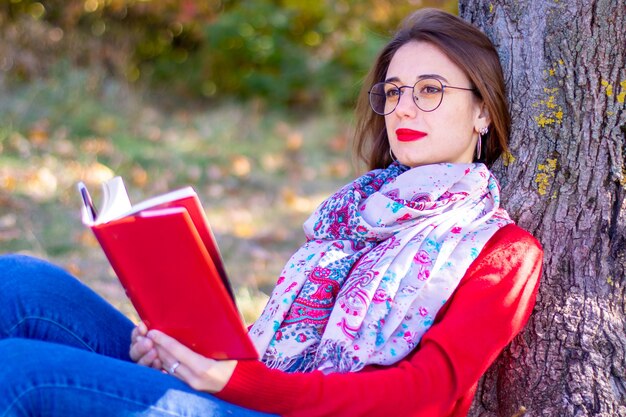 La signora in maglione rosso legge in natura. Ragazza e libro