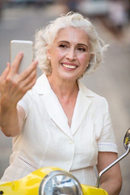 La signora sorridente esamina il telefono.