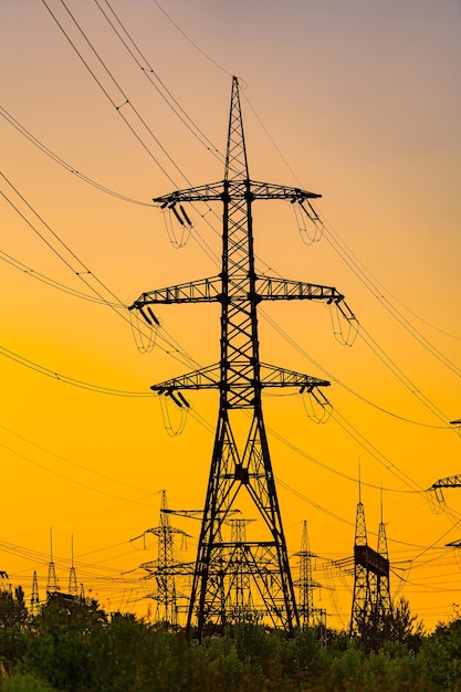La silhouette del pilone di trasmissione dell'elettricità serale. Linea elettrica nel bellissimo paesaggio della natura. Messa a fuoco selettiva.