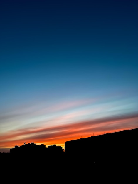 La silhouette della città sullo sfondo di un bellissimo cielo azzurro al tramonto e un tramonto viola