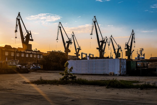 La silhouette delle gru portuali al tramonto. Tema industriale