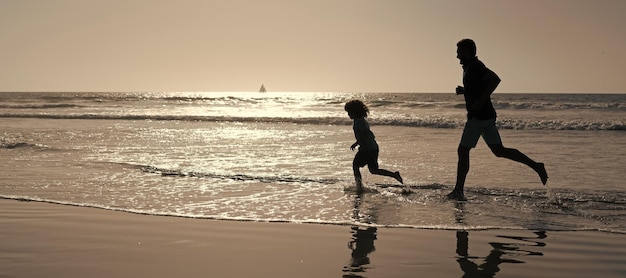 La silhouette di padre e figlio corre sulla spiaggia estiva all'aperto poster banner con spazio per la copia Papà e figlio