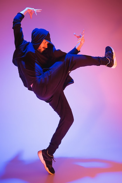 La silhouette di un giovane ballerino di break dance hip hop che balla su sfondo colorato