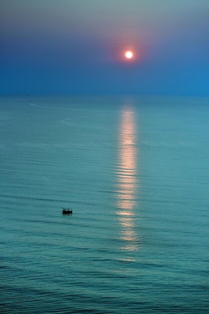 La siluetta del peschereccio sta navigando sul mare turchese nell'ora del tramonto