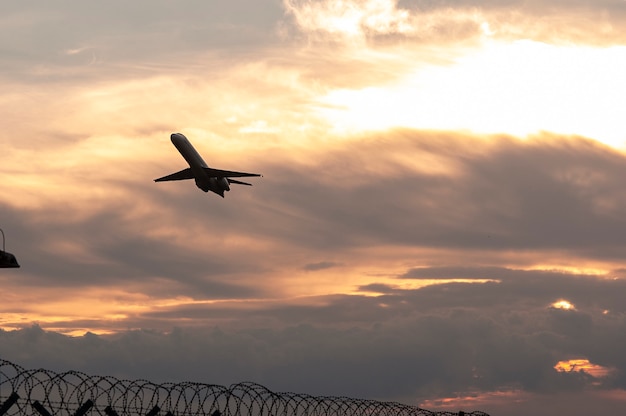 La siluetta di un aereo passeggeri che vola al tramonto decolla vicino all'aeroporto