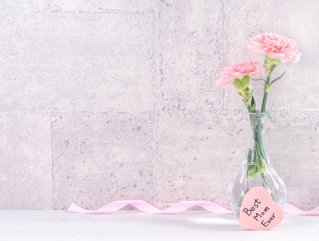 La sorpresa del giftbox fatto a mano per la festa della mamma augura la fotografia - bellissimi garofani in fiore con scatola di nastro rosa isolato su sfondo grigio design, close up, spazio di copia