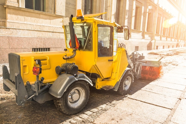 La spazzatrice urbana gialla pulisce lo sporco del terrapieno stradale con una spazzola rotonda