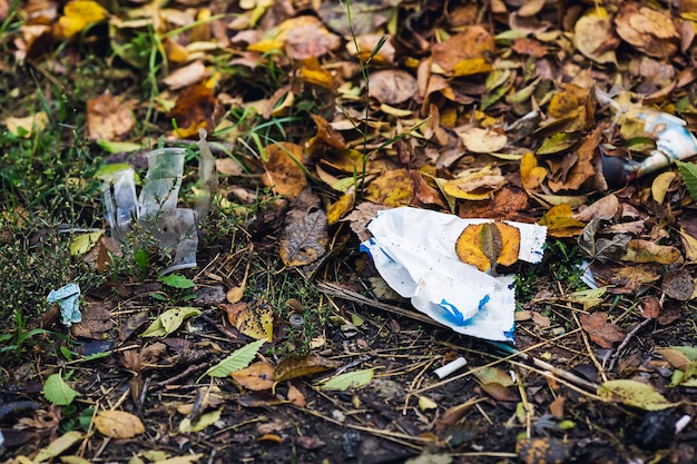 La spazzatura di plastica si trova tra le foglie. Concetto di inquinamento ambientale.