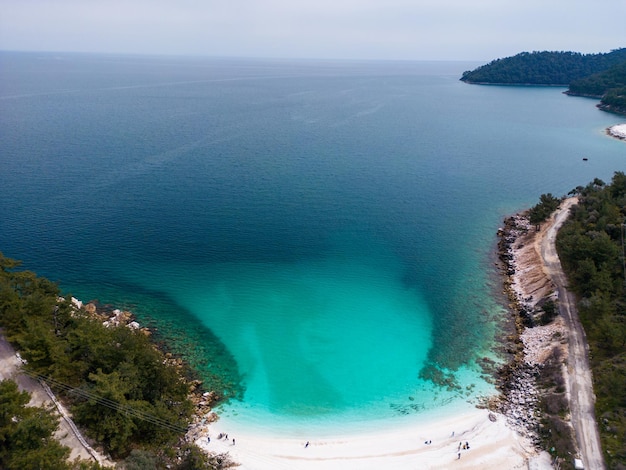 La spiaggia con ciottoli di marmo bianco e mare turchese sull'isola greca di Thassos Veduta aerea Il contrasto dei ciottoli bianchi incontaminati contro il mare blu vivido crea una vista affascinante