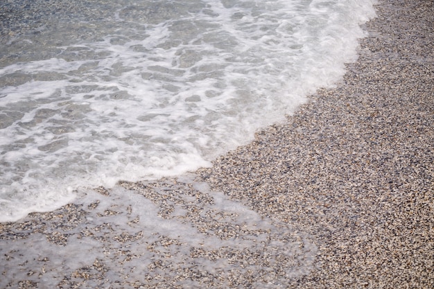 La spiaggia della costa mediterranea con onde di acqua azzurra. Brezza marina estiva. Messa a fuoco selettiva