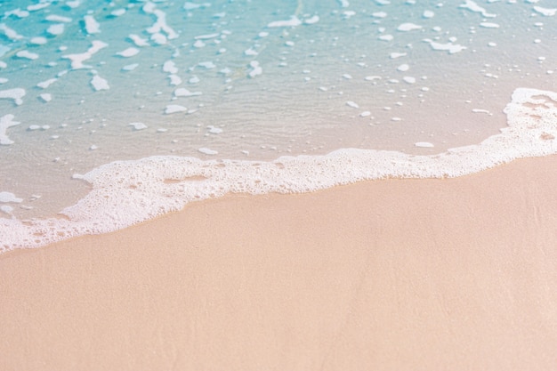 La spiaggia e la sabbia con l'acqua blu e l'onda spumeggiante nella spiaggia tropicale in Thailandia