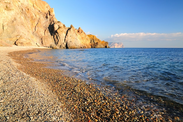 La spiaggia rocciosa è bagnata da calme onde del mare