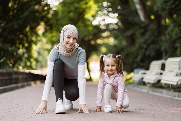 La sportiva madre araba e la sua graziosa figlia sulla pista da corsa si preparano a iniziare a correre