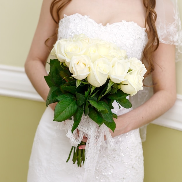 La sposa a un matrimonio con in mano un mazzo di fiori. La sposa in abito bianco a una cerimonia di matrimonio con un mazzo di rose.