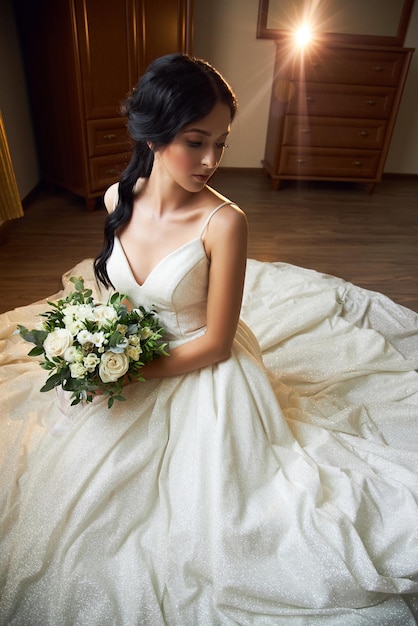 La sposa con un bellissimo abito bianco e un mazzo di fiori tra le mani sta aspettando la cerimonia di nozze. Bella donna con un bouquet da sposa tra le mani