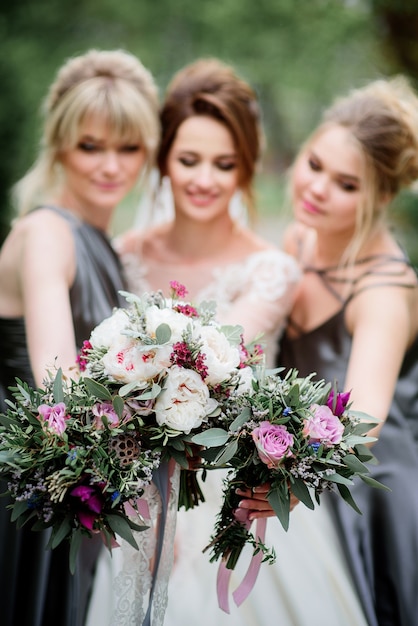 La sposa e le damigelle d&#39;onore graziose posano in un parco verde