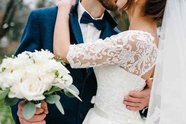 La sposa e lo sposo con un bouquet da sposa in piedi sulla cerimonia di nozze all'aperto nella natura