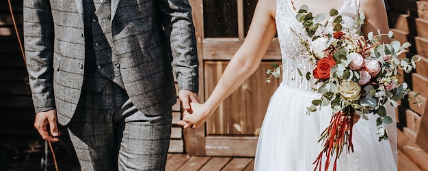 La sposa e lo sposo il giorno del matrimonio si abbracciano e mostrano amore con un bouquet da sposa di fiori di rosa