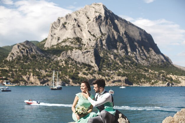 La sposa e lo sposo in natura in montagna vicino all'acqua