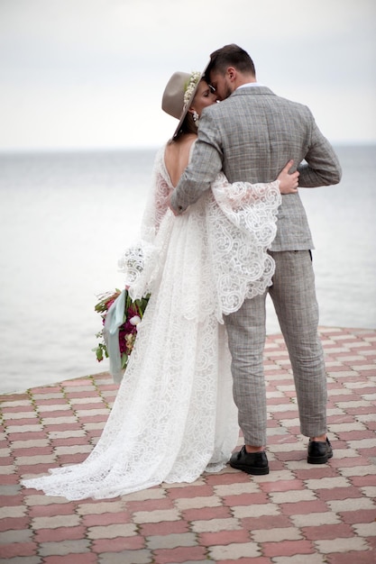 La sposa e lo sposo in piedi sul molo in mare durante la cerimonia nuziale