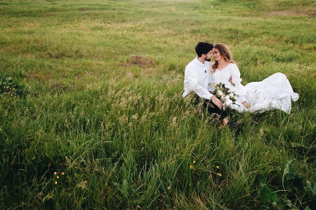 La sposa e lo sposo seduti sul campo erboso