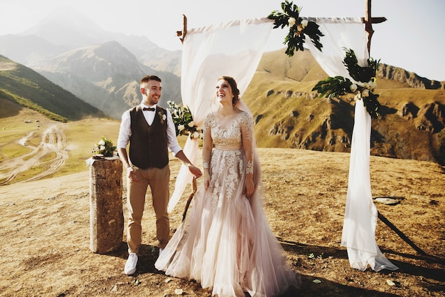 La sposa e lo sposo sembrano adorabili durante la cerimonia di nozze sulla cima della montagna