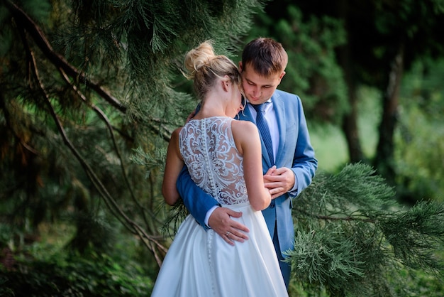 La sposa e lo sposo sembrano bellissime passeggiate in un parco estivo verde