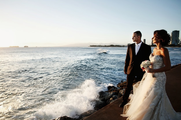 La sposa e lo sposo stanno a parte sulla riva dell&#39;oceano la sera