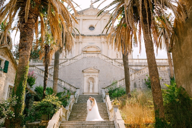 la sposa e lo sposo stanno abbracciando e tenendosi per mano sulle scale