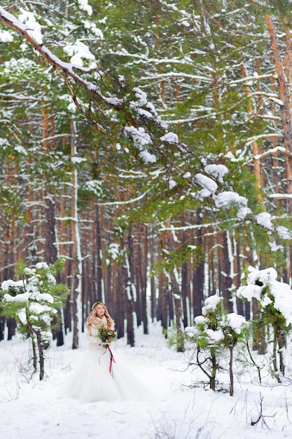 La sposa e lo sposo stanno sedendo sul tronco nella foresta dell'inverno.