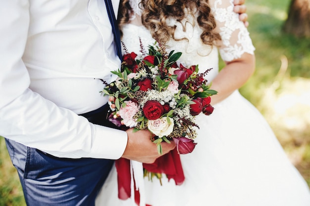 La sposa e lo sposo stanno tenendo il mazzo di nozze.