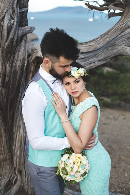 La sposa e lo sposo sulla natura in montagna vicino all'acqua