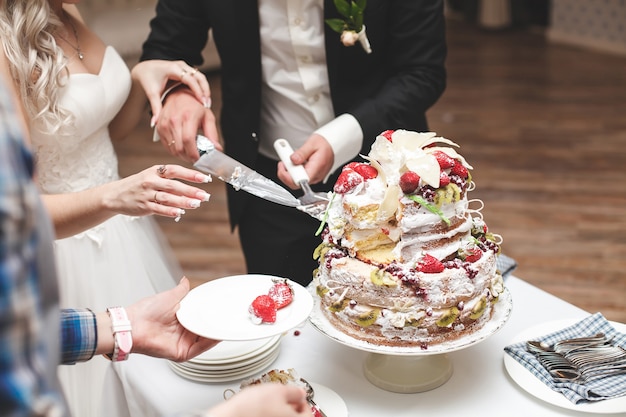 La sposa e lo sposo tagliano la torta nuziale.
