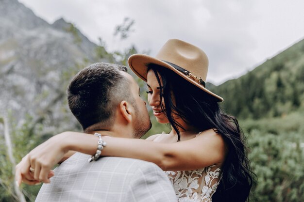 La sposa e lo sposo vicino al lago in montagna. Una coppia insieme sullo sfondo di un paesaggio montano. Lago Morskie Oko. Monti Tatra in Polonia