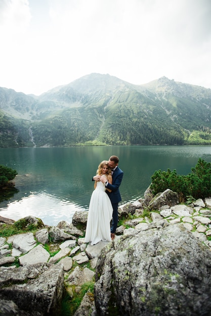 La sposa e lo sposo vicino al lago in montagna.