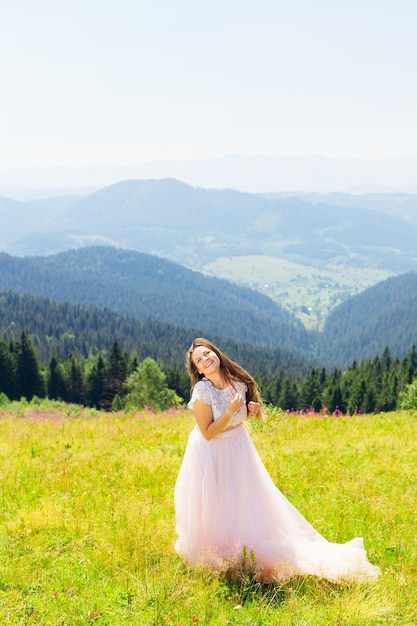 La sposa felice alza lo sguardo e sorride sullo sfondo di montagne fantastiche