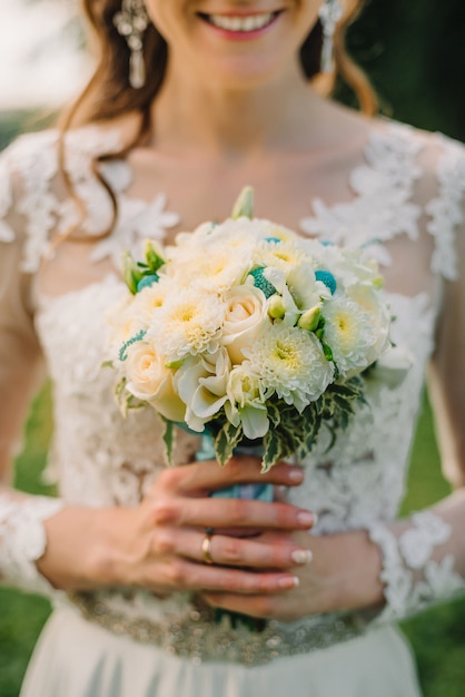 La sposa felice tiene un mazzo di nozze delle rose bianche