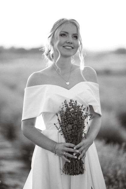 La sposa in abito bianco cammina sul campo di lavanda