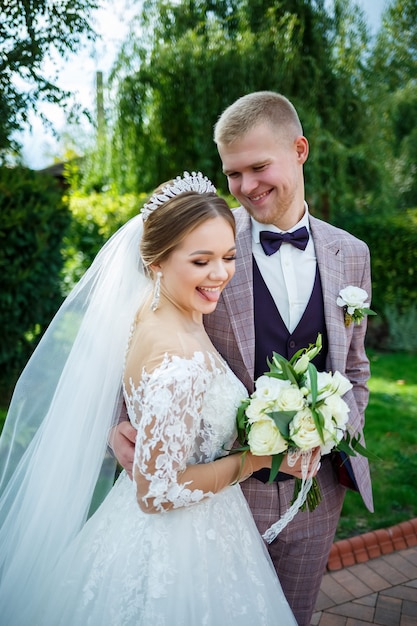 La sposa in abito bianco e lo sposo in costume si coccolano e passeggiano nel parco