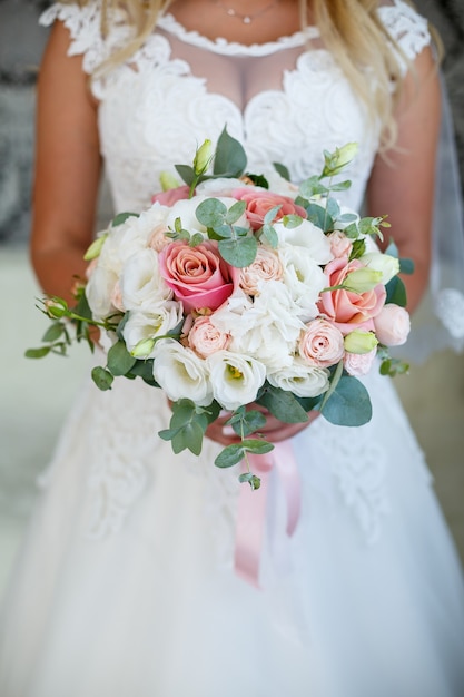 La sposa in abito bianco tiene un mazzo di fiori