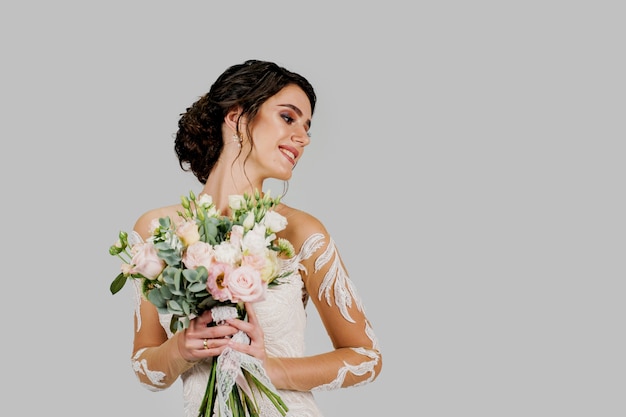 La sposa in abito da sposa bianco con bouquet guarda a destra