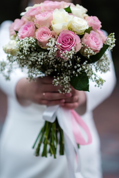 La sposa in abito da sposa bianco tiene in mano un mazzo di fiori bianchi peonie rose Matrimonio Sposi Delicato bouquet di benvenuto Bella decorazione di matrimoni con foglie