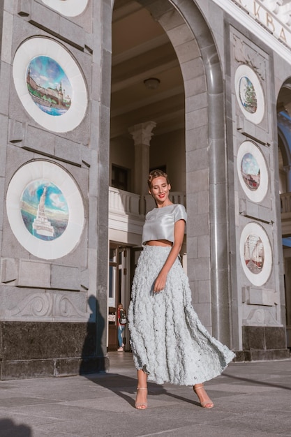 La sposa in abito di taffettà dolcemente turchese balla sul portico dell'edificio con l'architettura originale