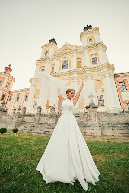 La sposa in un abito chic sta roteando vicino alla chiesa