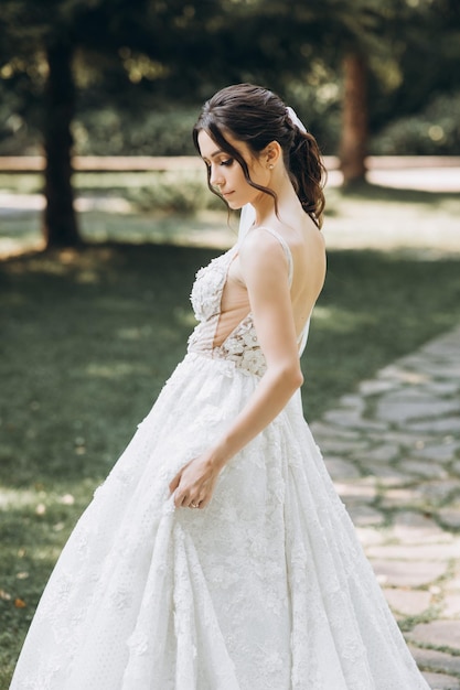 la sposa in un bellissimo abito bianco si trova in mezzo a una foresta verde