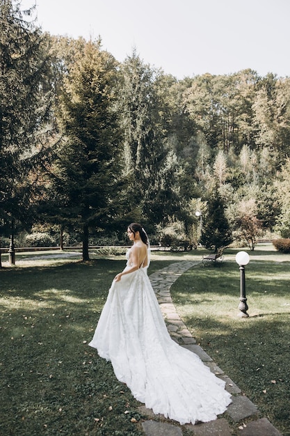 la sposa in un bellissimo abito bianco si trova in mezzo a una foresta verde